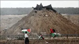  ?? KHALIL HAMRA / ASSOCIATED PRESS ?? A protester hangs a Palestinia­n flag on the fence in front of an Israeli observatio­n base during a protest Friday at the Gaza Strip’s border with Israel.