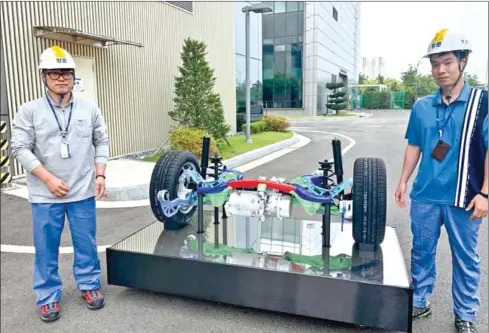  ??  ?? Lee Hong-woo (left), principal researcher at department materials forming research group of Posco Global R&D Centre, poses with suspension parts prototype his team developed in use of giga steel.