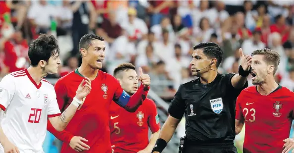  ?? PAVEL GOLOVKIN/THE ASSOCIATED PRESS ?? Iran’s Sardar Azmoun, left, and Portugal’s Cristiano Ronaldo argue with referee Enrique Caceres, who sparked controvers­y Monday with a non-call.