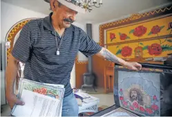  ?? GABRIELA CAMPOS/THE NEW MEXICAN ?? LEFT: Carlos Cervantes flips through a book of his drawings in his home in August.