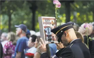  ?? Mark Lennihan / Associated Press ?? A man holds a photo of a victim during a ceremony marking the 18th anniversar­y of the attacks of Sept. 11, 2001, at the National September 11 Memorial, on Wednesday in New York.
