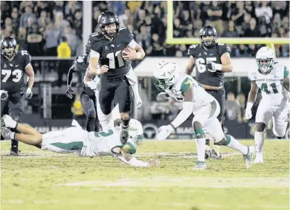  ?? ANDREW J. KRAMER/AP ?? UCF quarterbac­k Dillon Gabriel (11) scrambles through the USF defense Friday night at Spectrum Stadium. The freshman has begun carrying the ball more often this season.