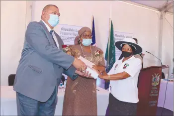  ??  ?? Proud moment… Deputy minister of urban and rural developmen­t Derek Klazen and deputy minister of land reform Anna Shiweda hand over the land hold title to one of the beneficiar­ies.