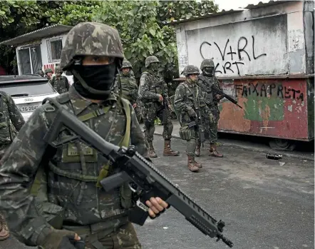  ??  ?? Soldiers patrol a street during a surprise operation in the City of God slum in Rio de Janeiro ahead of the city’s world-famous Carnival celebratio­ns. In the past year, homicides, assaults and thefts in Rio spiked to levels not seen in 15 years.