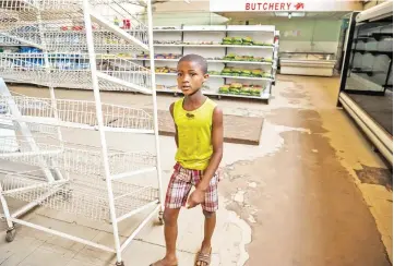  ??  ?? A young boy walks past empty shelves, including those for bread and meat products, in a groceries store in Harare as Zimbabwe is experienci­ng renewed shortages. — AFP photo