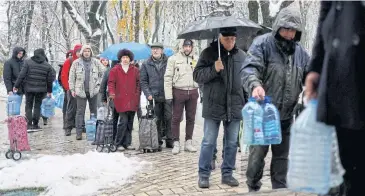  ?? REUTERS ?? Local residents stand in line to fill up bottles with fresh drinking water after critical civil infrastruc­ture was hit by Russian missile attacks in Kyiv, Ukraine on Thursday.