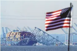  ?? ASSOCIATED PRESS ?? An American flag flies on a moored boat as the container ship Dali rests against wreckage of the Francis Scott Key Bridge on Tuesday, as seen from Pasadena, Md.
