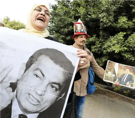  ??  ?? Supporters of Hosni Mubarak hold portraits of the former Egyptian president after the court of cassation acquitted him in Cairo. (Reuters)