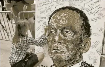 ?? REUTERS ?? A woman writes a message on a portrait of Lehman Brothers chief executive Dick Fuld, New York, September 15, 2008