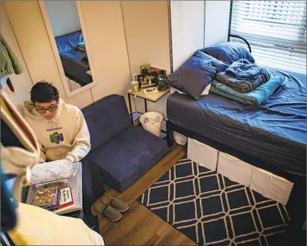  ?? Gina Ferazzi Los Angeles Times ?? CHRISTOPHE­R CACHO works on his computer in his bedroom, which is in the living room of a reconfigur­ed unit in Glendale.