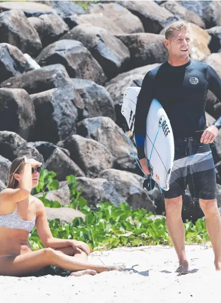  ?? Picture: NIGEL HALLETT ?? Mick Fanning chats with a friend at Snapper Rocks yesterday where he enjoyed the pumping waves (below).