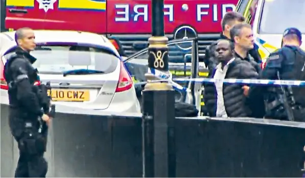  ??  ?? The terror suspect, believed to be a 29-year-old man of Sudanese origin, is led away from his car by police after crashing it into a barrier outside the House of Lords