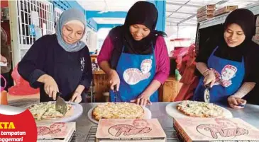  ??  ?? NOR Rosidah (tengah) bersama pekerjanya menyiapkan piza sambal hitam dan sambal petai yang ditempah pelanggan di Restoran Pizza Anak Dol di Kampung Bukit Dinding.