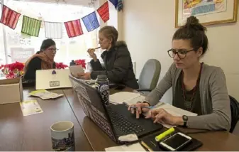  ??  ?? Laura Perkins, left, emergency response director for Casa San Jose, works with interns Katherine Anderson and Kelcey Bailey at the nonprofit’s offices in Beechview on Jan. 8.