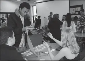  ??  ?? Symney Cameron, a Maurice J. McDonough High School junior, left, learns more about Russia from juniors Kyle Olenko and Natalia Theriault during the Internatio­nal Festival at the school.