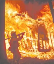  ?? AP PHOTO/NOAH BERGER ?? Firefighte­r Jose Corona sprays water earlier this month as flames from the Camp Fire consume a home in Magalia, Calif. A massive new federal report warns that extreme weather disasters are worsening.