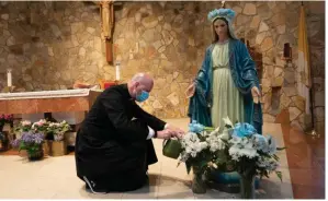  ?? (The New York Times/James Estrin) ?? Coronaviru­s restrictio­ns forced the Rev. Peter Purpura to close Our Lady of Hope Catholic Church in Queens, where he is shown caring for flowers.