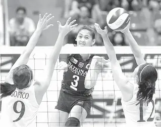  ?? FILE PHOTO ?? National University’s Jaja Santiago unleashes a powerful hit against Ateneo de Manila University players during a match in the UAAP women’s volleyball tournament.