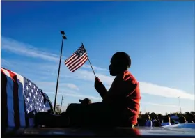  ?? (AP/Brynn Anderson) ?? Xavier Watts, 9, waves an American flag Nov. 15 during a campaign rally for Georgia Democratic U.S. Senate candidates Jon Ossoff and Raphael Warnock in Marietta, Ga.