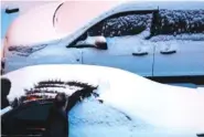  ??  ?? A man brushes snow off his car in a parking lot behind the Days Inn on April 3 in Rochester, Minn.