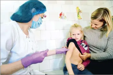  ?? SERGEI SUPINSKY/AFP ?? A nurse injects a measles vaccine into a girl in a pediatric polyclinic in Kiev on January 15.