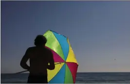  ?? JAE C. HONG — THE ASSOCIATED PRESS FILE ?? A man folds his umbrella on the beach in Laguna Beach on Aug. 7, 2018.