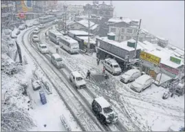  ?? DEEPAK SANSTA /HT ?? Vehicles plying on the snow-covered road in the Sanjauli area of Shimla on Thursday.