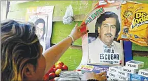  ??  ?? Een vrouw plakt een poster van de overleden Colombiaan­se drugsbaron Pablo Escobar. (Foto: ANP)