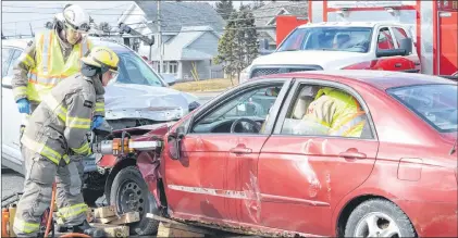  ?? JOE GIBBONS/THE TELEGRAM ?? A member of the Goulds Volunteer Fire Department used the Jaws of Life to cut open the driver side door of the vehicle that was struck head-on in the mock collision. First responders then “treated” the injured victim played by Elizabeth Johnson.