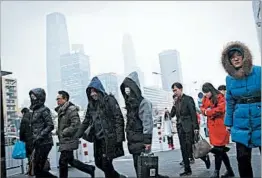  ?? ANDY WONG/AP ?? Commuters, some wearing masks, walk to a subway station during the evening rush hour in Beijing. Lawyers have filed suit against the capital and surroundin­g regions over smog.