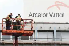  ??  ?? Workers stand near the logo of Arcelormit­tal, the world's largest producer of steel, at the steel plant in Ghent, Belgium. — Reuters