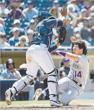  ?? Denis Poroy, Getty Images ?? Rockies catcher Tony Wolters scores ahead of the throw to San Diego Padres counterpar­t Francisco Mejia during the eighth inning Sunday at Petco Park.