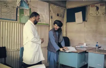  ?? BRAM JANSSEN/AP ?? Taliban member Mohammad Javid Ahmadi, right, talks to a doctor in the hospital last month in Mirbacha Kot, Afghanista­n. Ahmadi, who has no medical training or experience, was appointed as the new manager of the hospital.