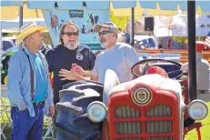  ??  ?? From left, Ken Sanchez, Jeff Barrows and Joseph Gutierrez talk tractors at this year’s annual Running of the Tractors on May 4.