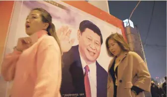  ?? — AFP ?? This photo taken on October 24 shows women walking past a roadside poster of Chinese President Xi Jinping, after the closing of the 19th Communist Party Congress in Beijing.