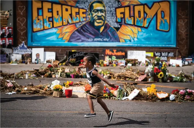  ??  ?? Carter Sims, 3, of Pine Island runs past a mural at the George Floyd memorial outside Cup Foods on June 25, 2020, exactly one month after George Floyd died at this corner. (Photo by Leila Navidi/star Tribune)