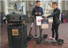  ?? Michael Macor / The Chronicle ?? Leo Dubler (left) and Bastien Ruch, visiting from Switzerlan­d, check out two Bird scooters on Market Street.