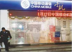  ??  ?? A security guard uses his mobile phone in front of a China Mobile store in Guangzhou, China.