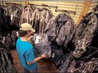  ?? Arkansas Democrat-Gazette/STATON BREIDENTHA­L ?? Ryan Rickford of Benton looks at camouflage clothing Thursday while shopping at Bass Pro Shops Outdoor World in Little Rock.