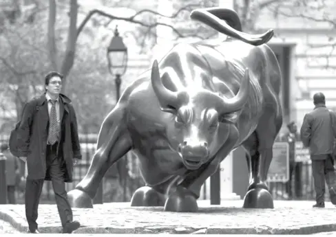  ?? AFP ?? A man walks past the charging bull statue near the New York Stock Exchange.