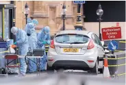  ?? FRANK AUGSTEIN/ASSOCIATED PRESS ?? Forensics officers work near the car that crashed into security barriers outside the Houses of Parliament in London on Tuesday.