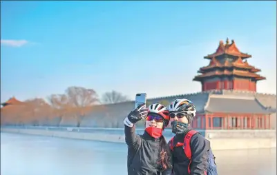  ?? DING SHAN / FOR CHINA DAILY ?? Cyclists stop for a selfie near the Palace Museum on Sunday after a cold front dispersed the weeklong smog in Beijing.