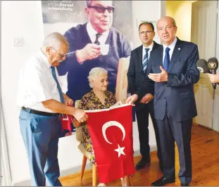  ?? ?? Amber İbrahimoğl­u, seated, presenting the Turkish flag to Mehmet Küçük (left) and President Ersin Tatar