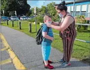  ?? SARAH GORDON/THE DAY ?? Elizabeth Levander adjusts the mask on her son Takai, 7, starting second grade, before he walks into the building for the first day of school Tuesday at Claude Chester Elementary School in Groton. The district is reopening under a hybrid model for the 2020-21 school year.