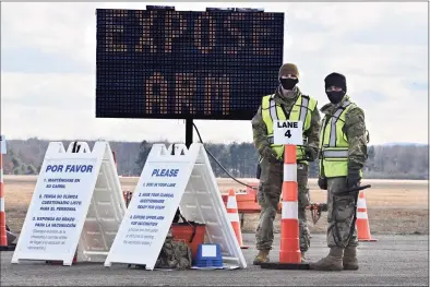  ?? Jessica Hill / Associated Press ?? Connecticu­t National Guard members wait to check in vehicles for Connecticu­t’s largest COVID-19 vaccinatio­n drive-thru clinic in East Hartford on Monday.