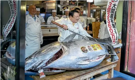  ?? BLOOMBERG ?? Kiyoshi Kimura, president of Kiyomura Corp., poses with a newly-purchased tuna at a Sushizanma­i restaurant in Tokyo. The record price was more than double the previous high set in 2013.