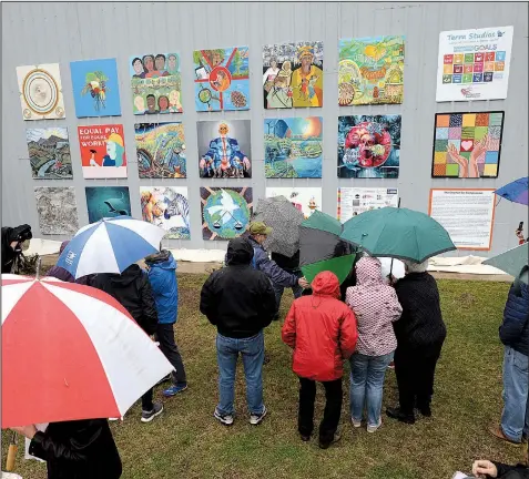  ?? NWA Democrat-Gazette/ANDY SHUPE ?? A crowd gathers in the rain April 13 to watch the unveiling of “The Better World Mural” at Terra Studios in Fayettevil­le.