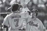  ?? THE ASSOCIATED PRESS ?? The Atlanta Braves’ Kurt Suzuki, right, celebrates with Dansby Swanson after hitting a home run off the Oakland Athletics’ John Axford in the 12th inning Sunday in Oakland, Calif.