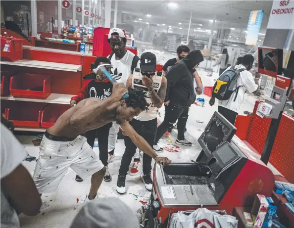  ??  ?? MAYHEM: A looter targets a cash register at a Target store in Minneapoli­s as rioting engulfed the city of St Paul for a second night.
Picture: AP