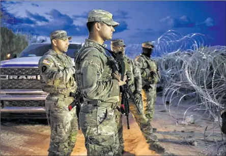  ?? Robert Gauthier Los Angeles Times ?? NATIONAL GUARD troops watch migrants gather on the banks of the Rio Grande in Eagle Pass, Texas, in September. Fifty-three percent of respondent­s in a Monmouth University poll this month support building a wall along the U.S.-Mexico border, up from 48% in 2015.